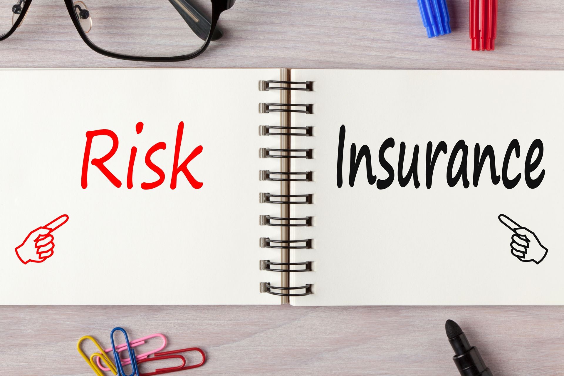 Risk and Insurance written on notebook on wooden desk with marker pen and glasses.Business Concept.Top view.